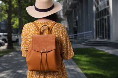 Photo of Young woman with stylish backpack on city street, back view