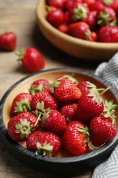 Delicious ripe strawberries on wooden plate, closeup