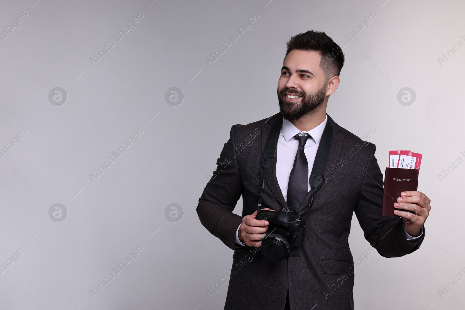 Photo of Happy businessman with passport, tickets and camera on grey background. Space for text