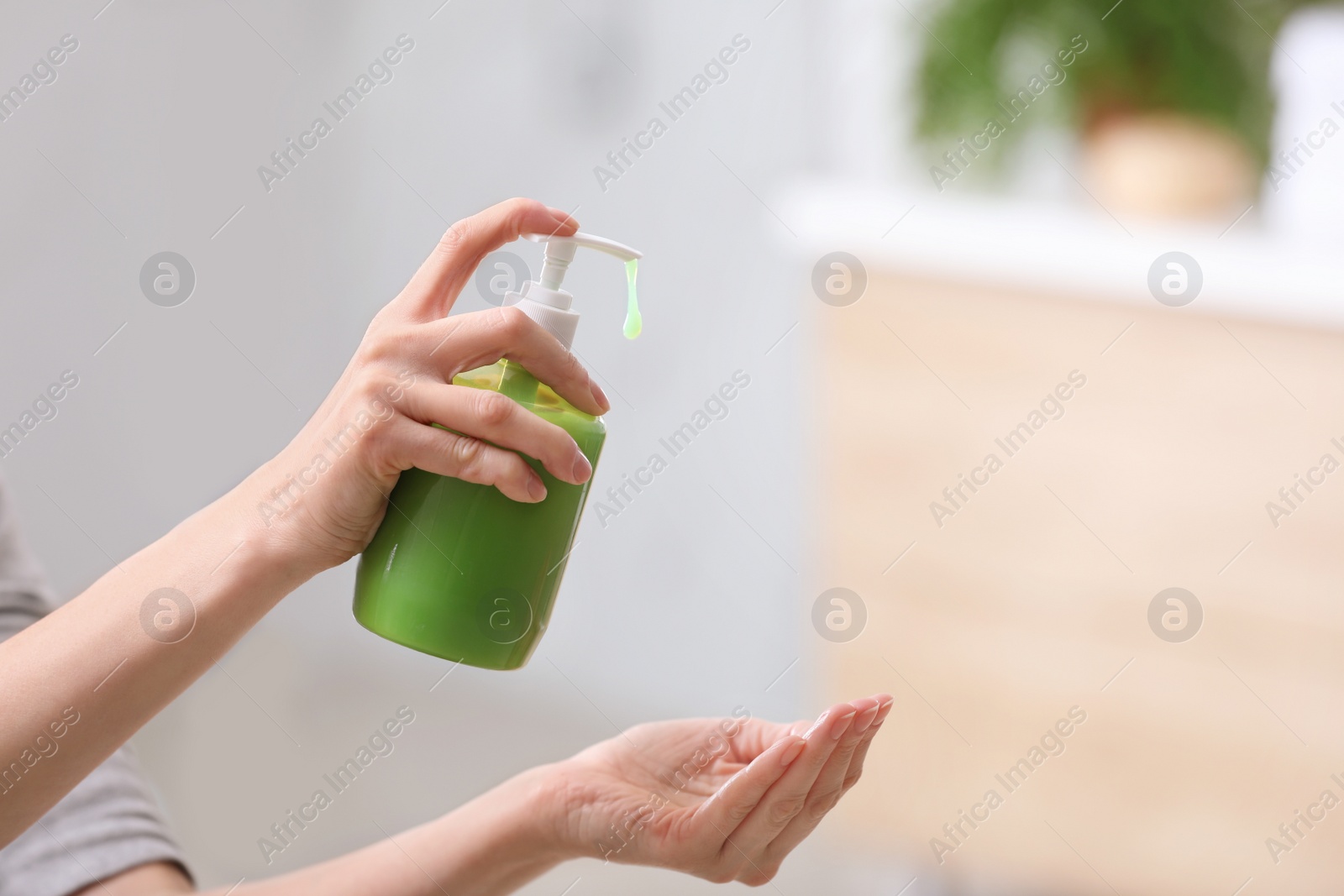 Photo of Woman with soap dispenser on blurred background, closeup. Space for text