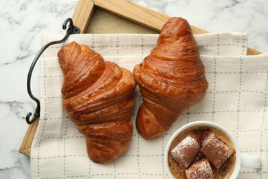 Photo of Tasty croissants served with cup of hot drink on white marble table, top view