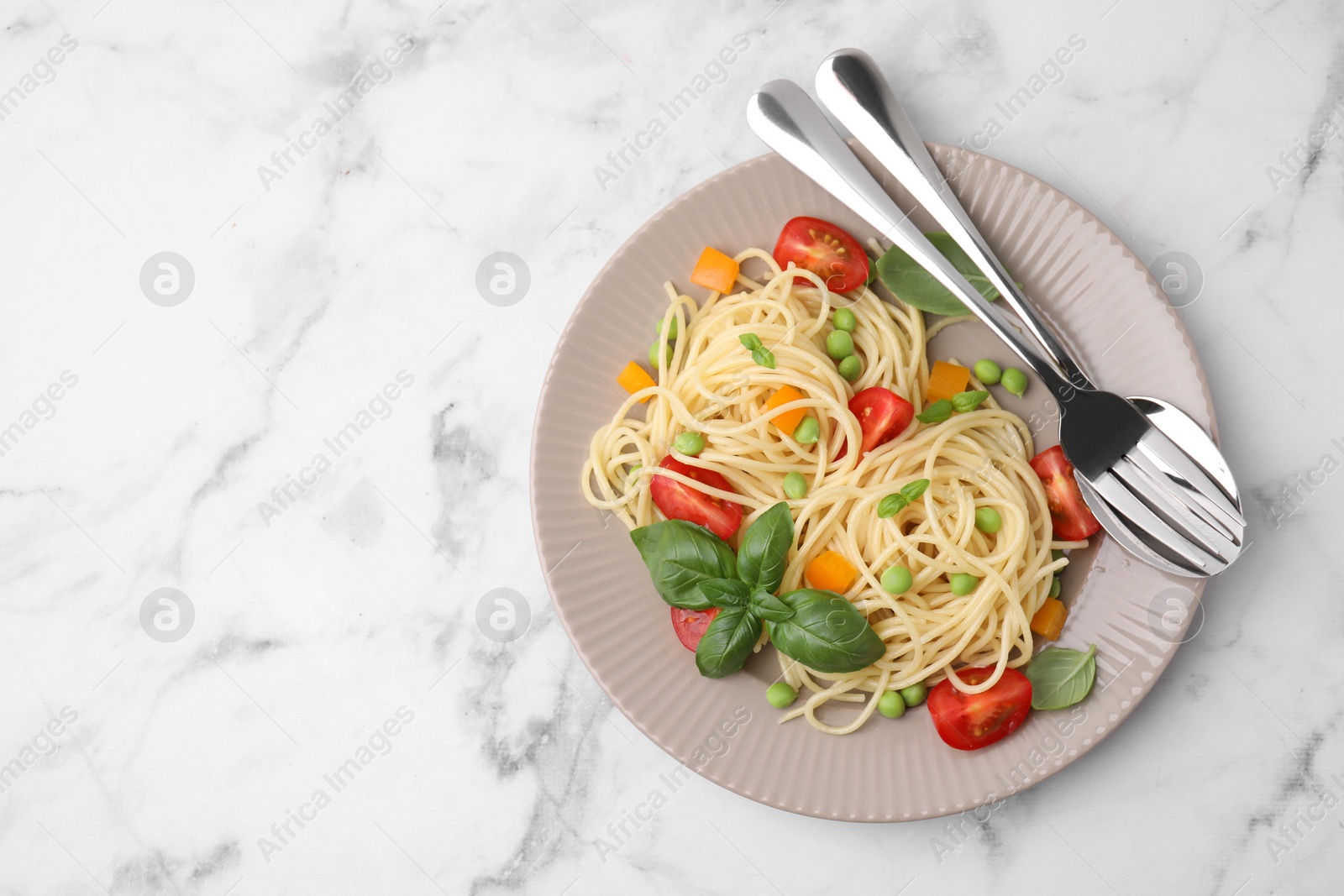 Photo of Plate of delicious pasta primavera and cutlery on white marble table, top view. Space for text