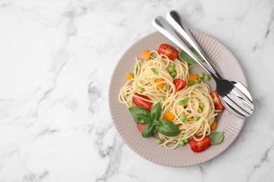 Plate of delicious pasta primavera and cutlery on white marble table, top view. Space for text