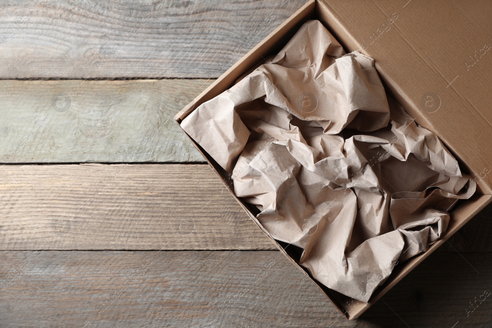 Photo of Box of waste paper on wooden table, top view. Space for text