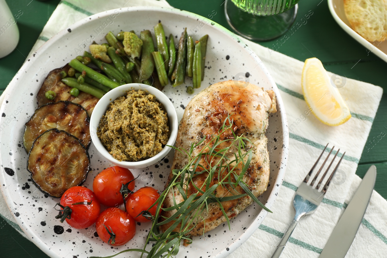 Photo of Tasty chicken, vegetables with tarragon and pesto sauce served on table, above view