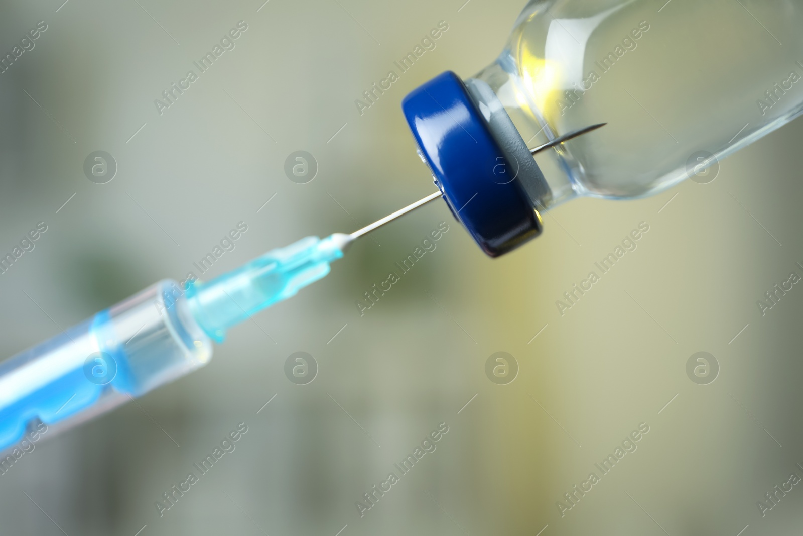 Photo of Filling syringe with medication from vial against blurred background, closeup. Vaccination and immunization