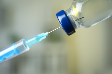 Photo of Filling syringe with medication from vial against blurred background, closeup. Vaccination and immunization