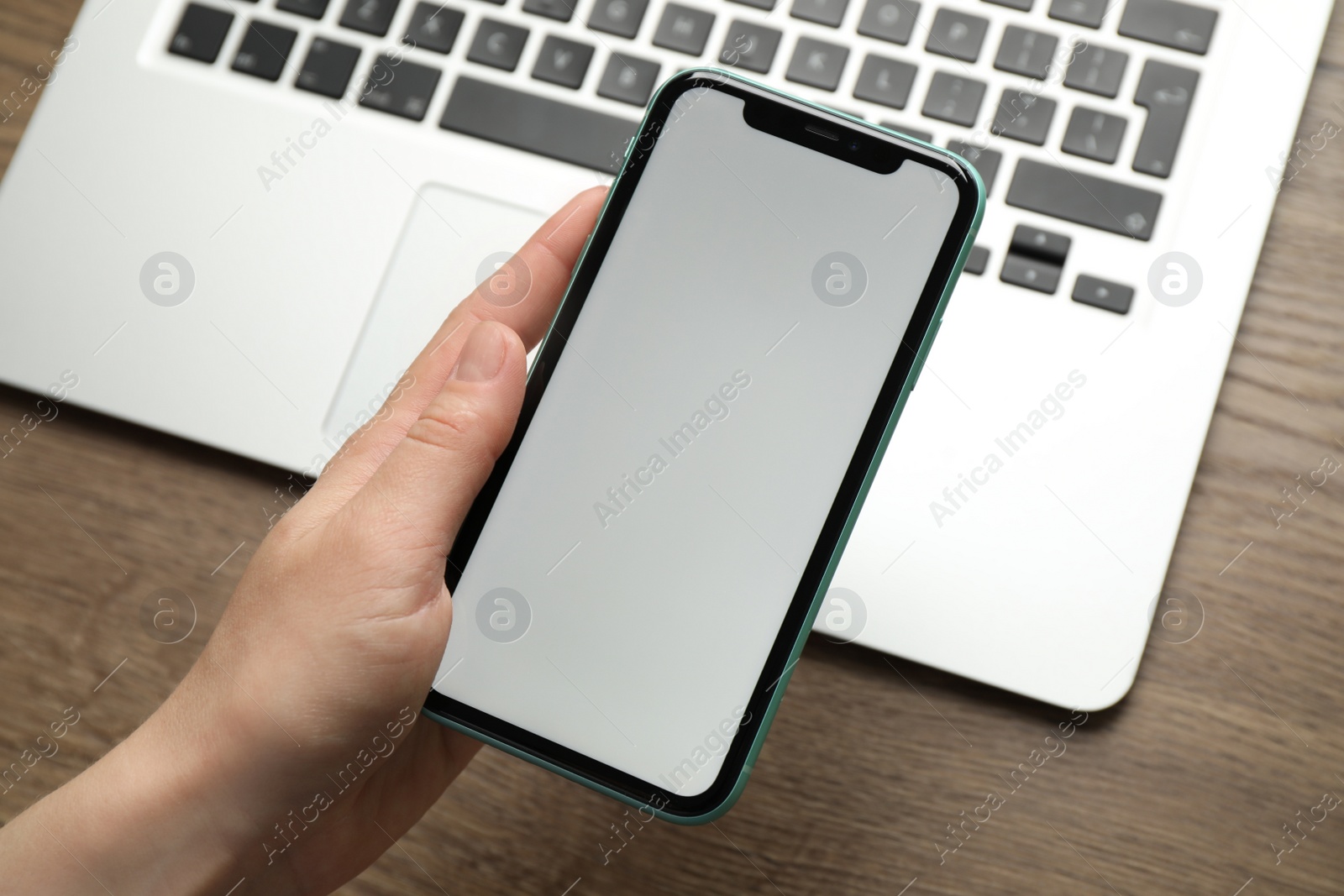 Photo of MYKOLAIV, UKRAINE - JULY 8, 2020: Woman holding Iphone 11 Pro Max with blank screen at workplace, closeup