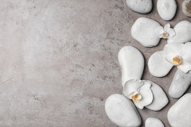 Photo of Flat lay composition with spa stones and orchid flowers on grey background. Space for text