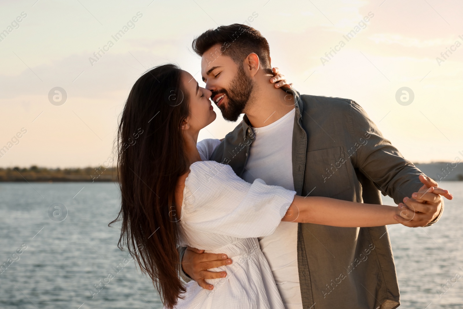 Photo of Happy couple dancing and kissing near river