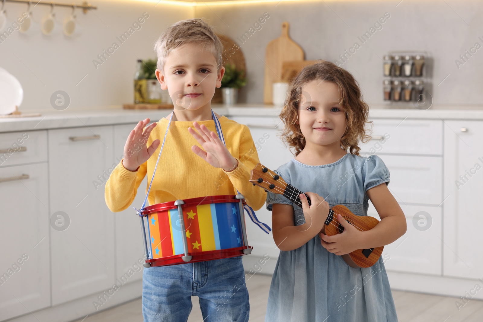 Photo of Little children playing toy musical instruments in kitchen