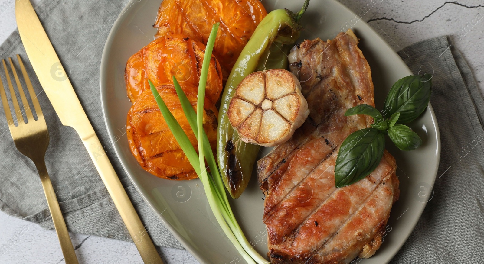 Photo of Delicious grilled meat and vegetables served on light grey table, flat lay