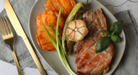 Delicious grilled meat and vegetables served on light grey table, flat lay