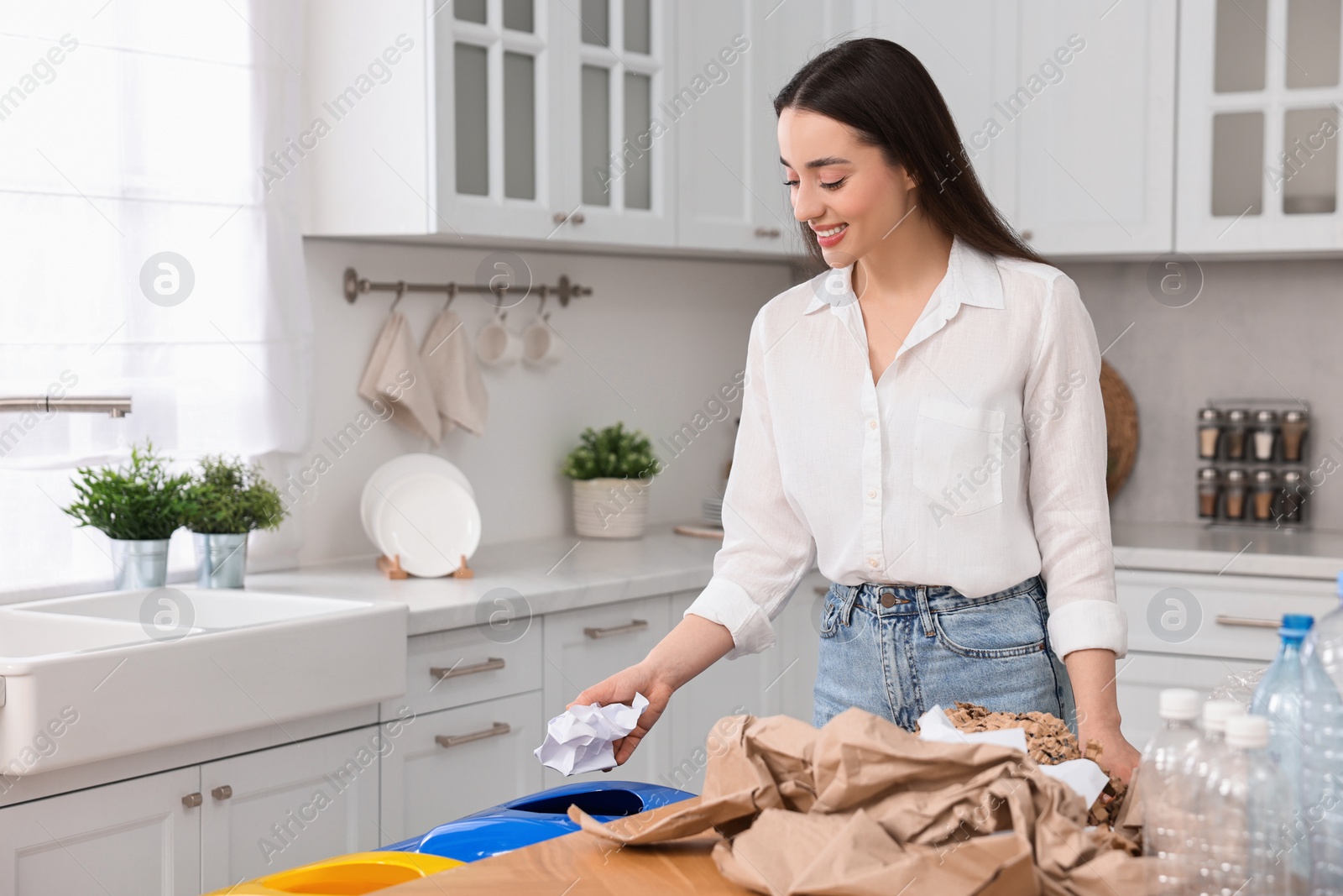 Photo of Smiling woman separating garbage in kitchen. Space for text