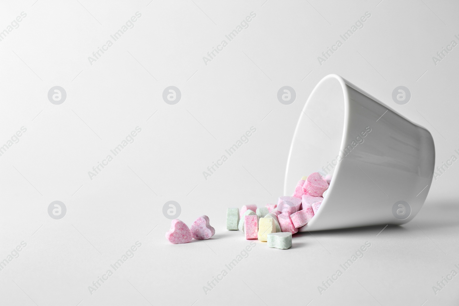 Photo of Small heart shaped candies and bowl on white background. Space for text