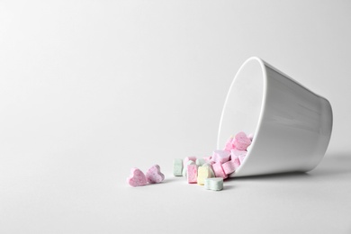 Photo of Small heart shaped candies and bowl on white background. Space for text