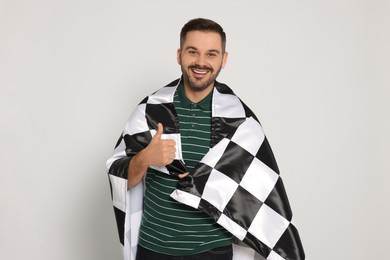 Photo of Man with checkered flag showing thumb up on white background