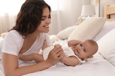 Photo of Happy young mother with her cute baby on bed at home