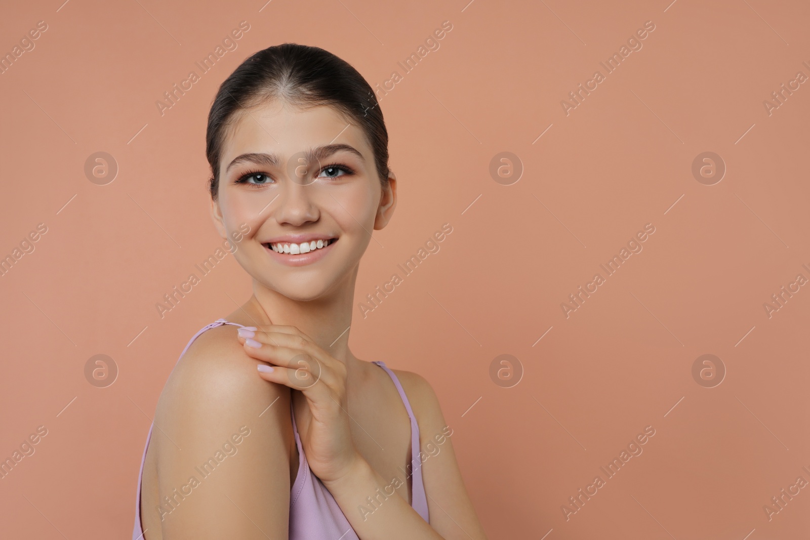 Photo of Portrait of pretty girl on pale coral background, space for text. Beautiful face with perfect smooth skin