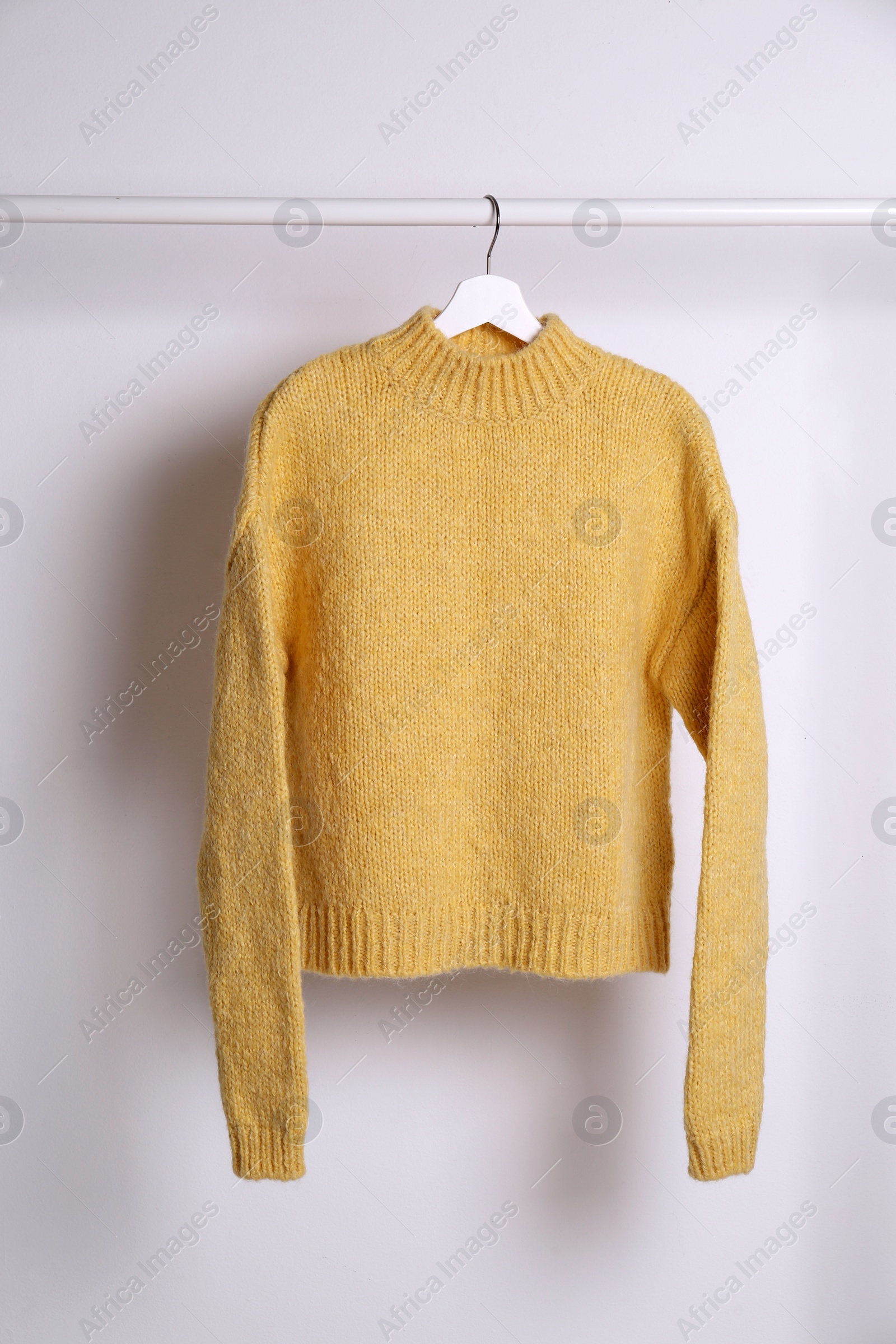 Photo of Warm sweater hanging on rack against white background