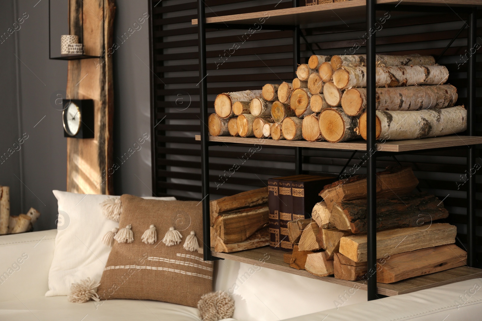 Photo of Shelving unit with stacked firewood and books near wall in room. Idea for interior design
