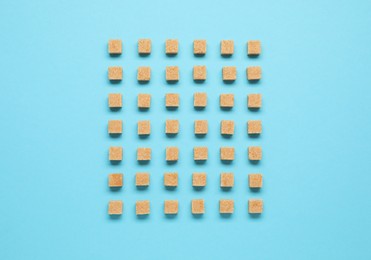 Brown sugar cubes on turquoise background, flat lay