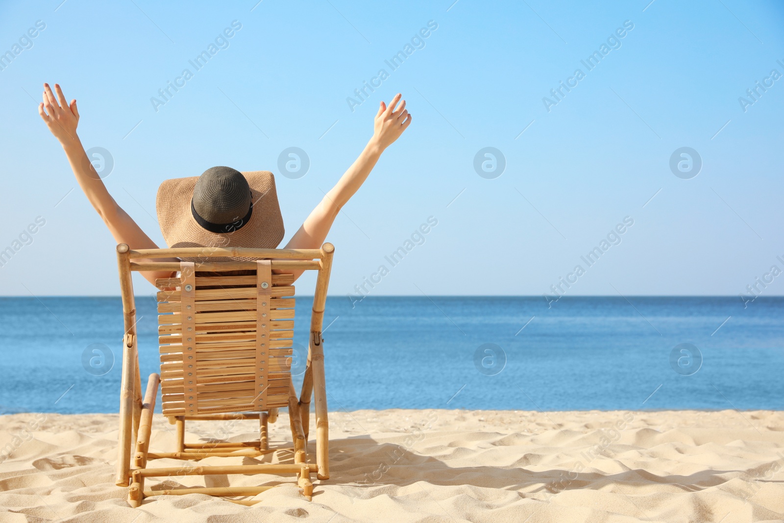 Photo of Young woman relaxing in deck chair on sandy beach