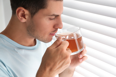 Photo of Man with cup of tea near window. Lazy morning