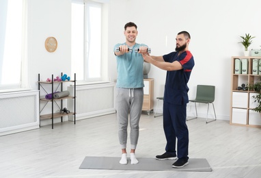 Photo of Physiotherapist working with patient in clinic. Rehabilitation therapy