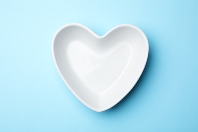 Photo of Heart shaped plate on color background, top view