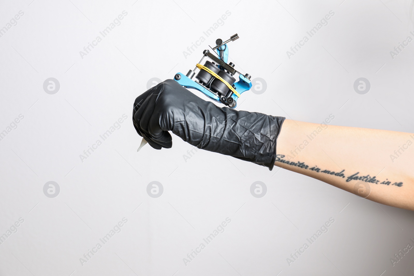 Photo of Professional tattoo artist with machine on white background, closeup