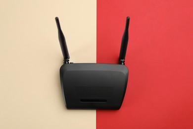 Modern Wi-Fi router on color background, top view