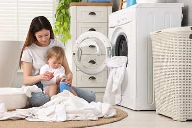 Mother with her daughter washing baby clothes in bathroom