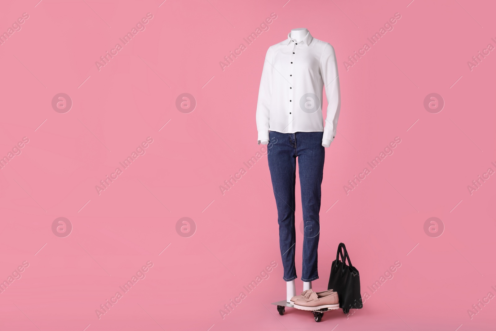 Photo of Female mannequin with shoes and bag dressed in white shirt and jeans on pink background, space for text. Stylish outfit