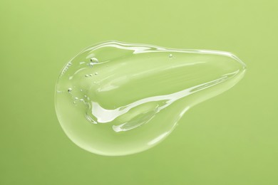 Sample of cleansing gel on green background, top view. Cosmetic product
