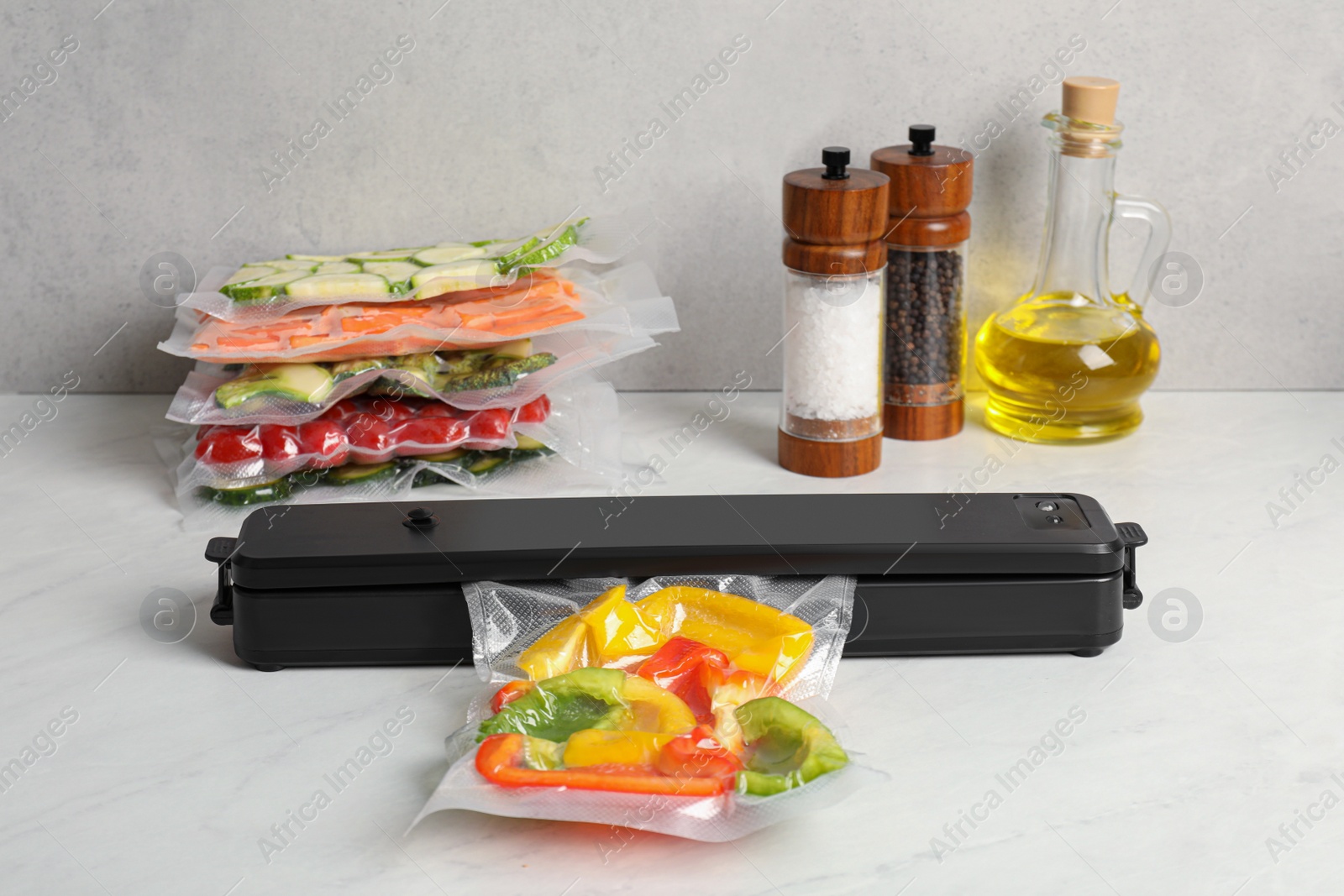 Photo of Sealer for vacuum packing with plastic bag of bell peppers on white table