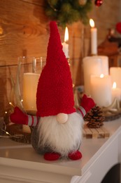 Cute Christmas gnome and festive decorations on mantelpiece in room