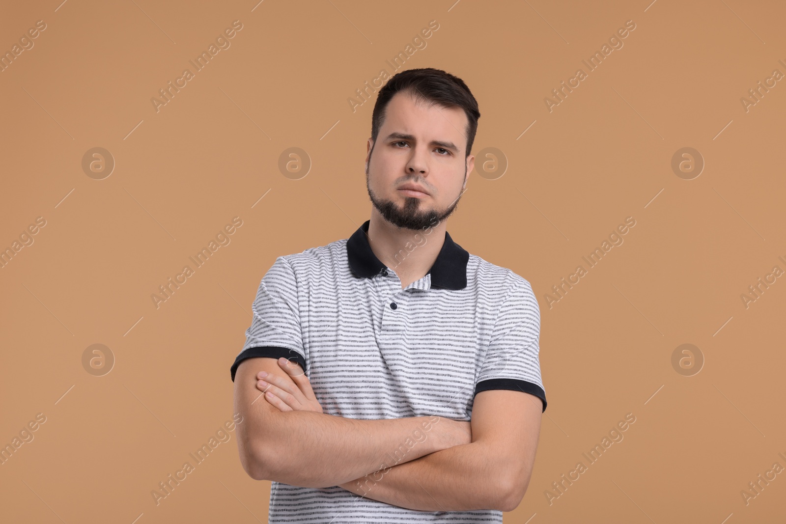Photo of Portrait of sad man with crossed arms on beige background
