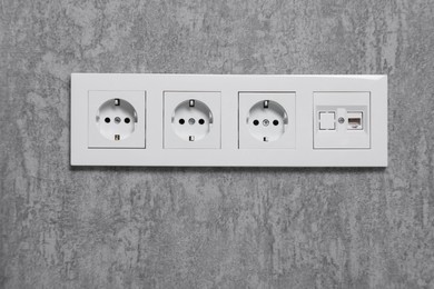 Electric power sockets on grey wall indoors