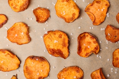 Photo of Sweet potato chips with salt on color background, flat lay