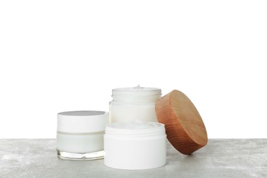 Photo of Jars of hand cream on gray table against white background