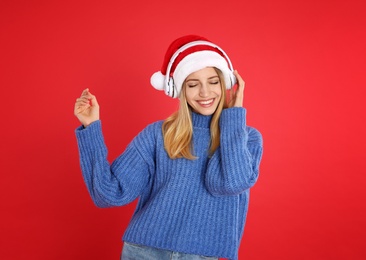 Happy woman with headphones on red background. Christmas music