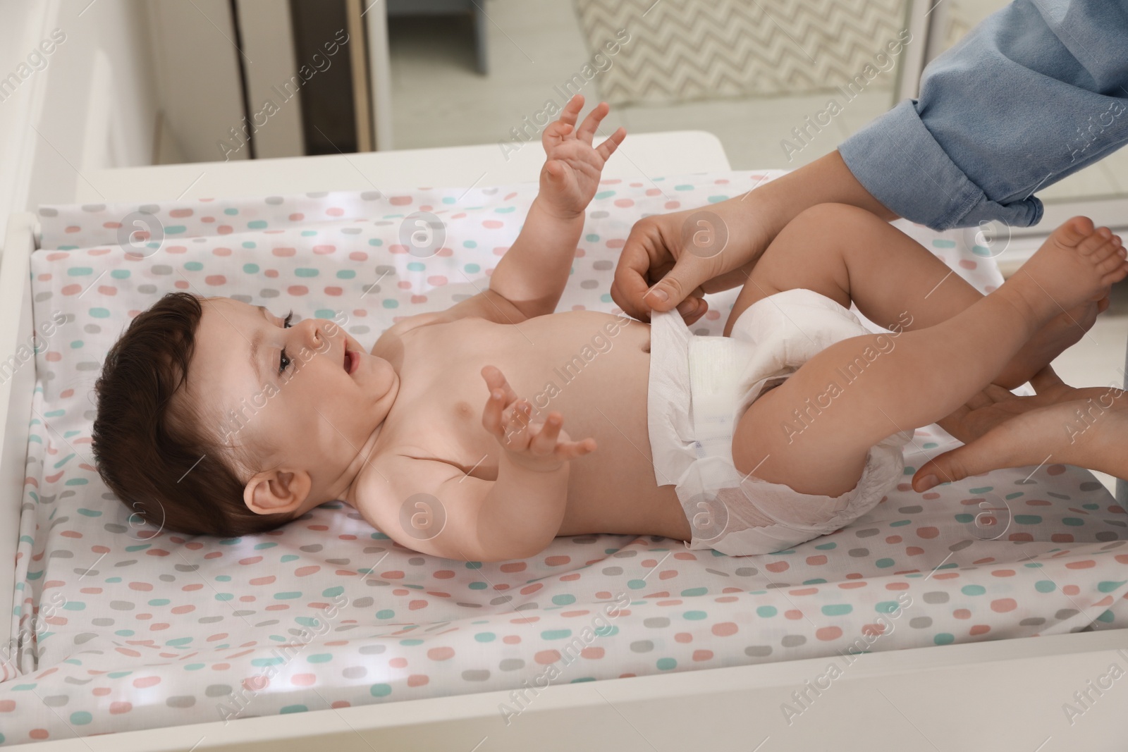 Photo of Mother changing baby's diaper on table at home, closeup