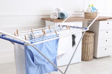 Photo of Clean laundry hanging on drying rack indoors