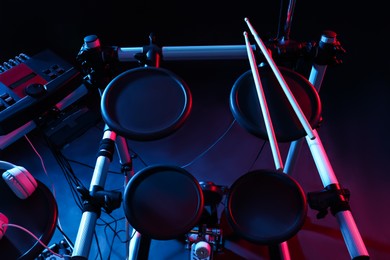 Photo of Modern electronic drum kit on dark background, color toned. Musical instrument