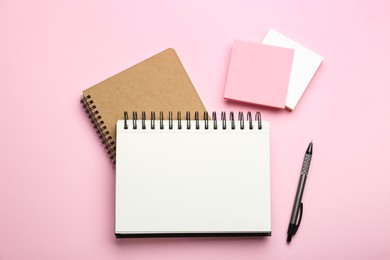 Photo of Notebooks, pen and sticky notes on pink background, flat lay