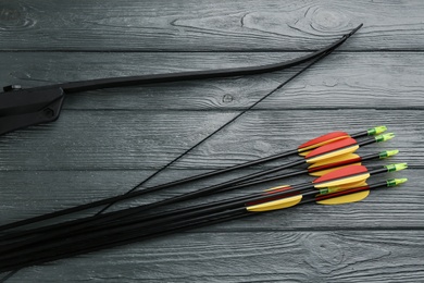 Photo of Plastic arrows and bow on grey wooden table, flat lay. Archery sports equipment