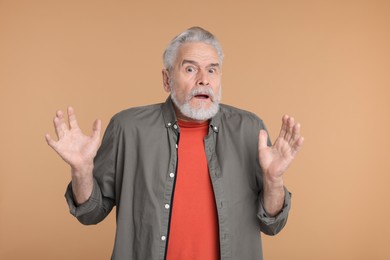 Photo of Portrait of surprised senior man on beige background