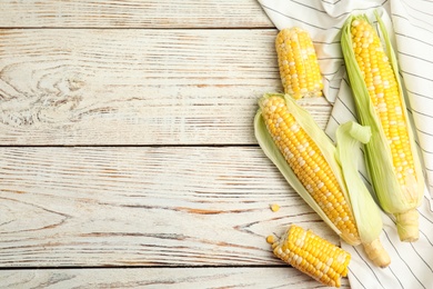 Tasty sweet corn cobs on white wooden table, flat lay. Space for text