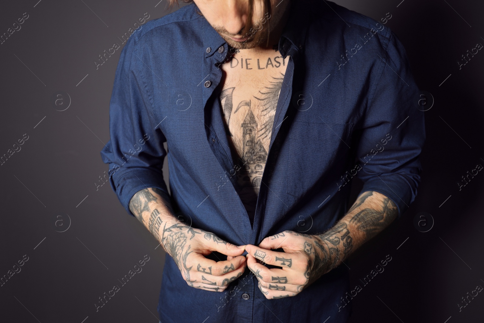 Photo of Young man with tattoos on body against black background, closeup